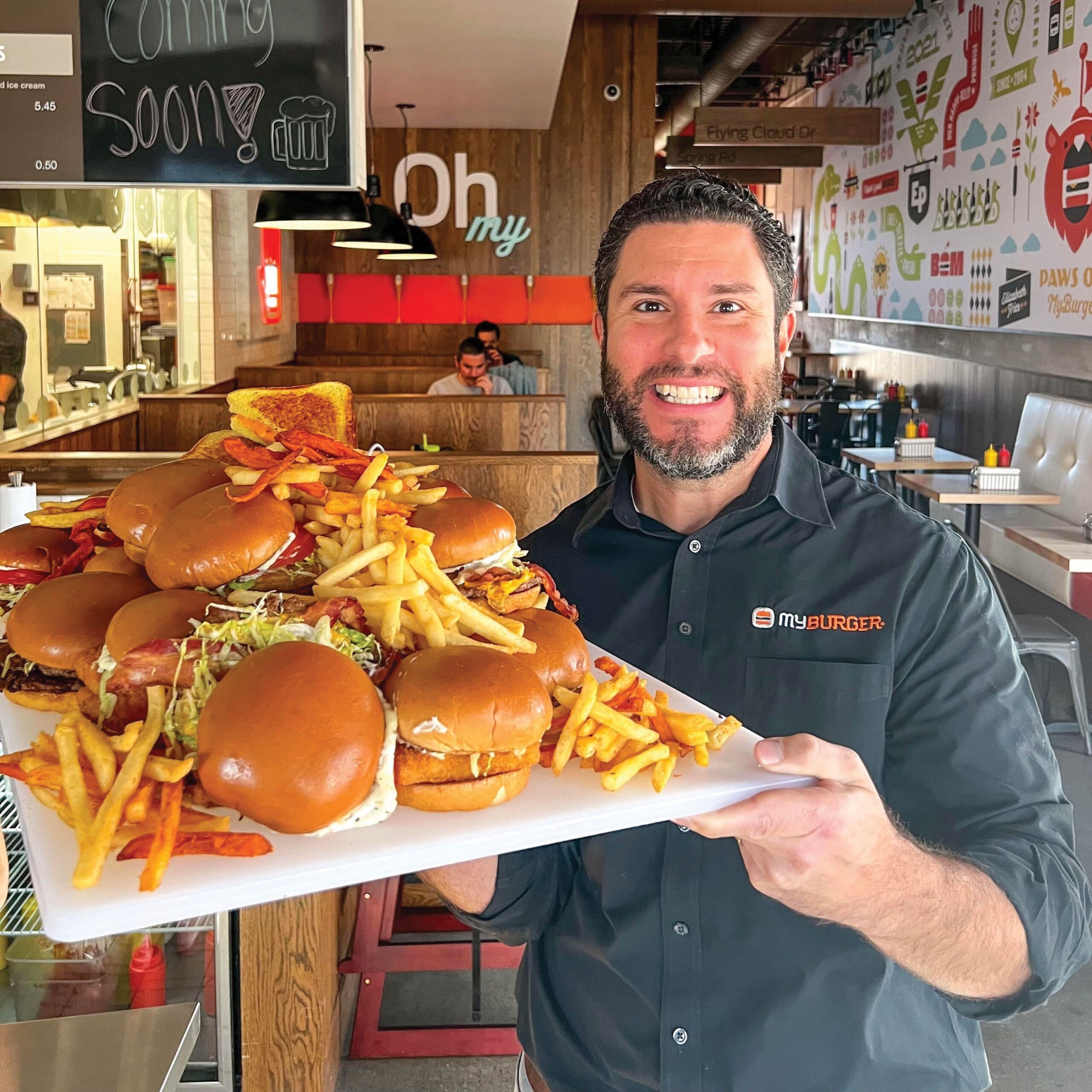 Paul Abdo with a platter of fries and burgers at his My Burger location.