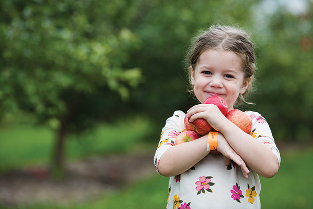 A child holds apples at Apple Jack Orchards in Delano