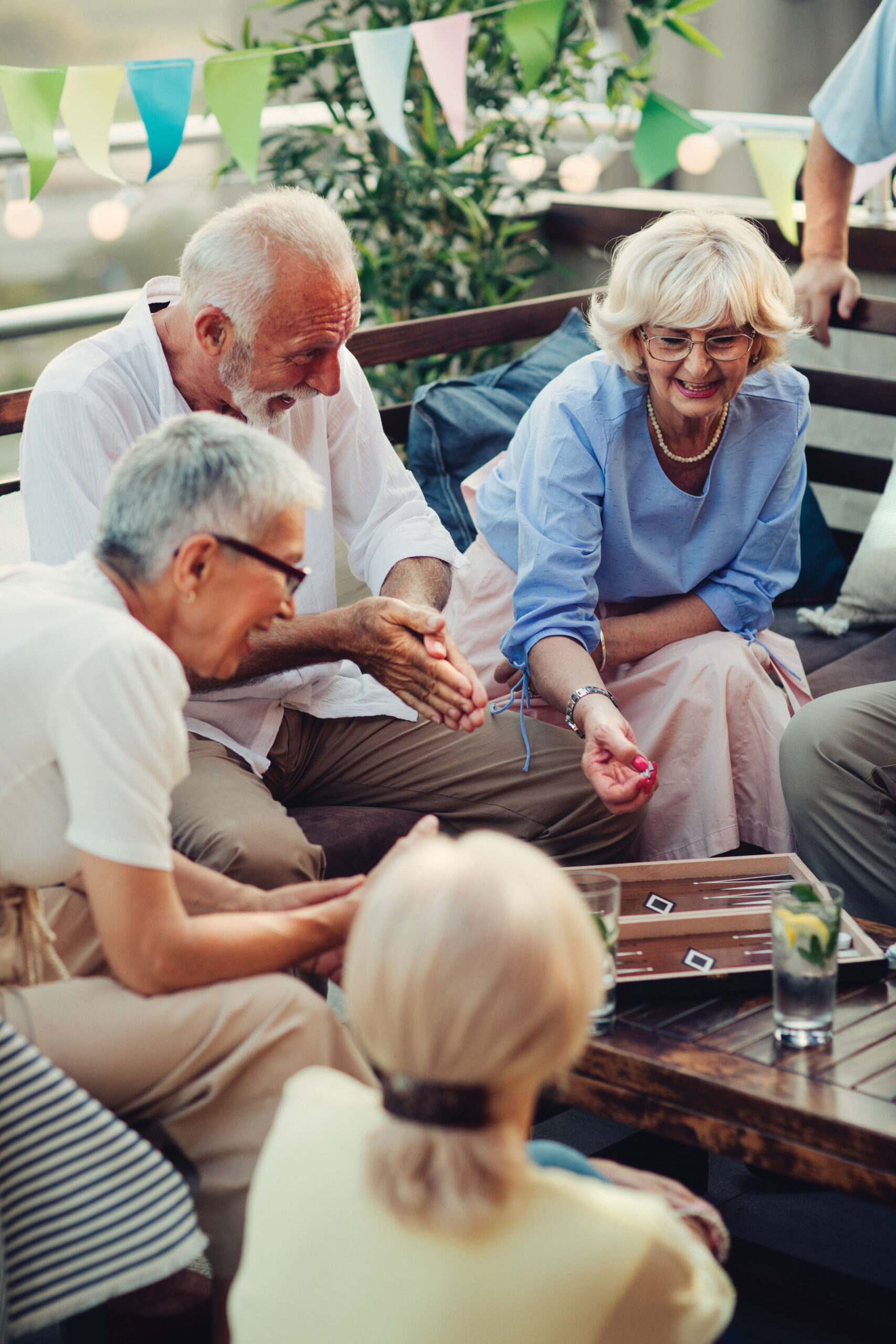 Group of seniors playing a dice game on an outdoor patio.