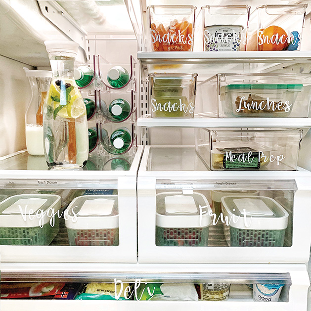 A fridge organized with clear, labeled bins for snacks, lunches, meal prep, veggies and fruit.