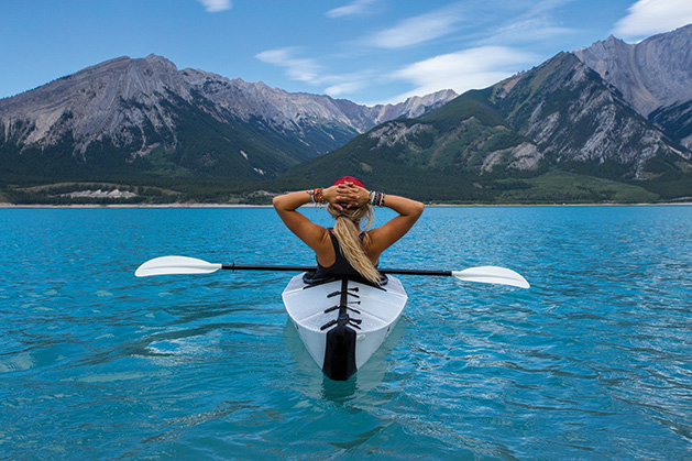 A woman in a kayak looks at some mountains ahead.
