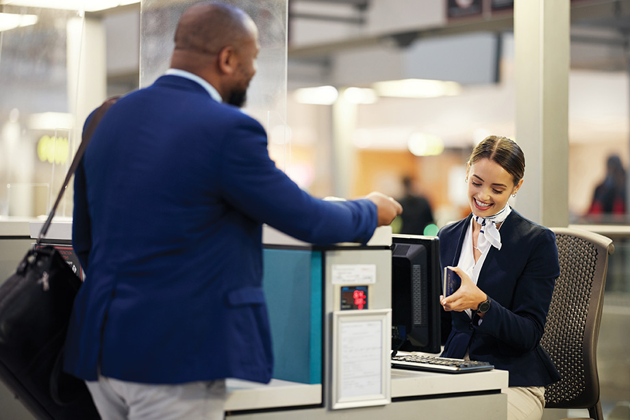Businessman, airport and passenger assistant checking passport documents for check in at terminal counter. Black male traveler and service agent in travel security or immigration for airline control