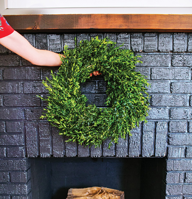 A fireplace with a wreath hanging above it.