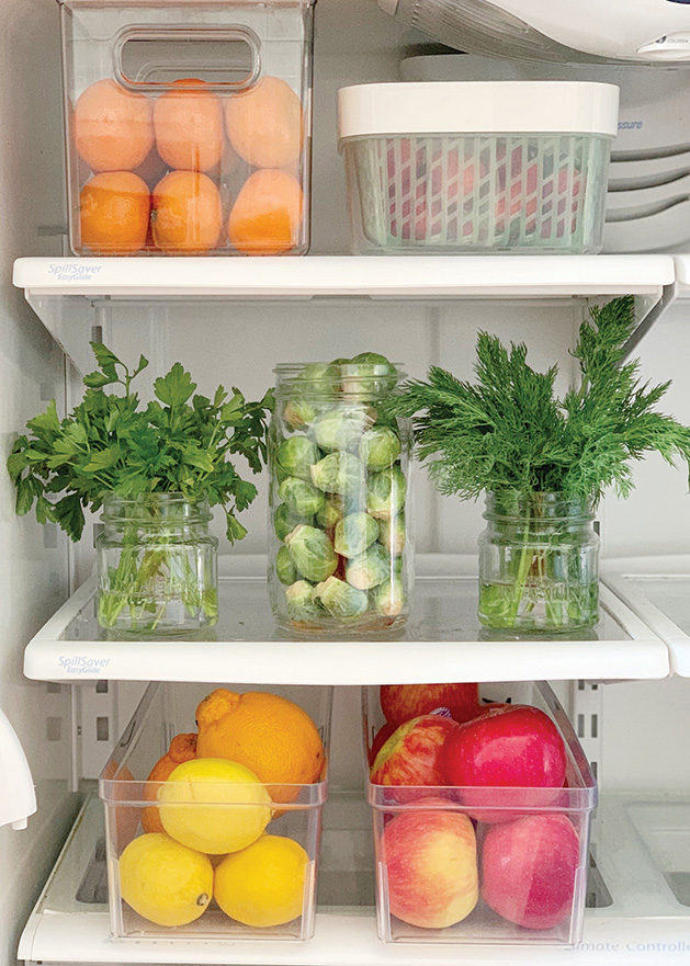 Plastic containers filled with food sit on the shelves of a well-organized fridge.