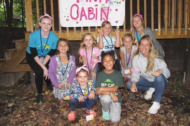 Campers at Camp Erin pose in front of their "Pink Cabin"