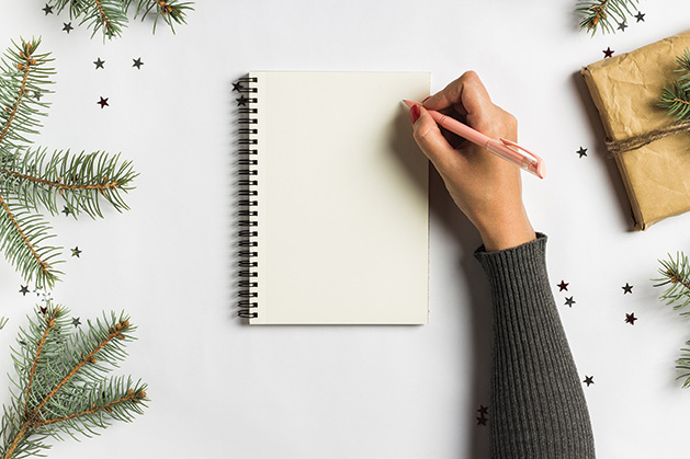 A person writes a to-do list to stay organized during the holidays.