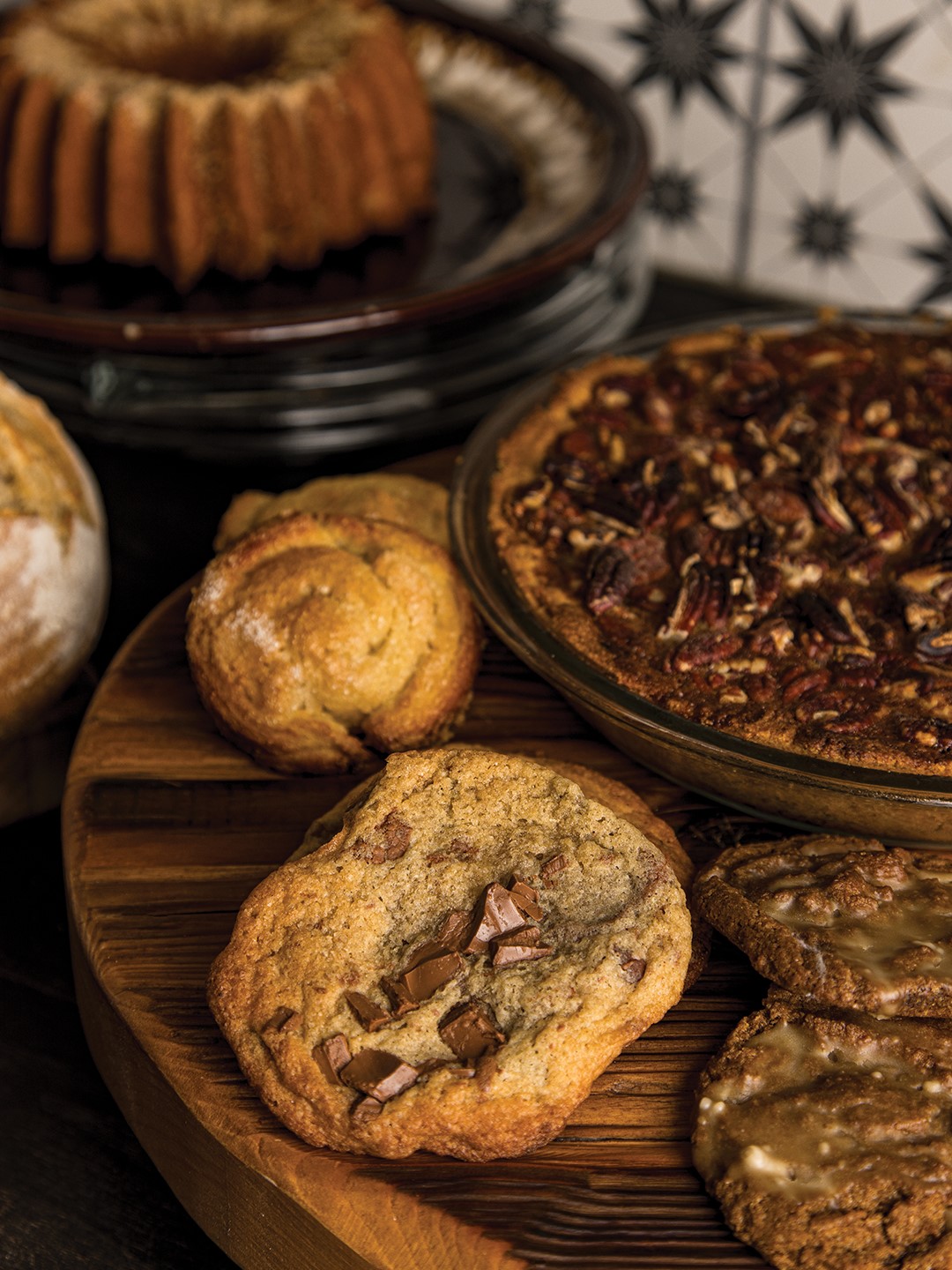 A pecan pie is nestled in an array of pastries and treats, including kouign-amann, sourdough chocolate chip cookies, and molasses cookies.