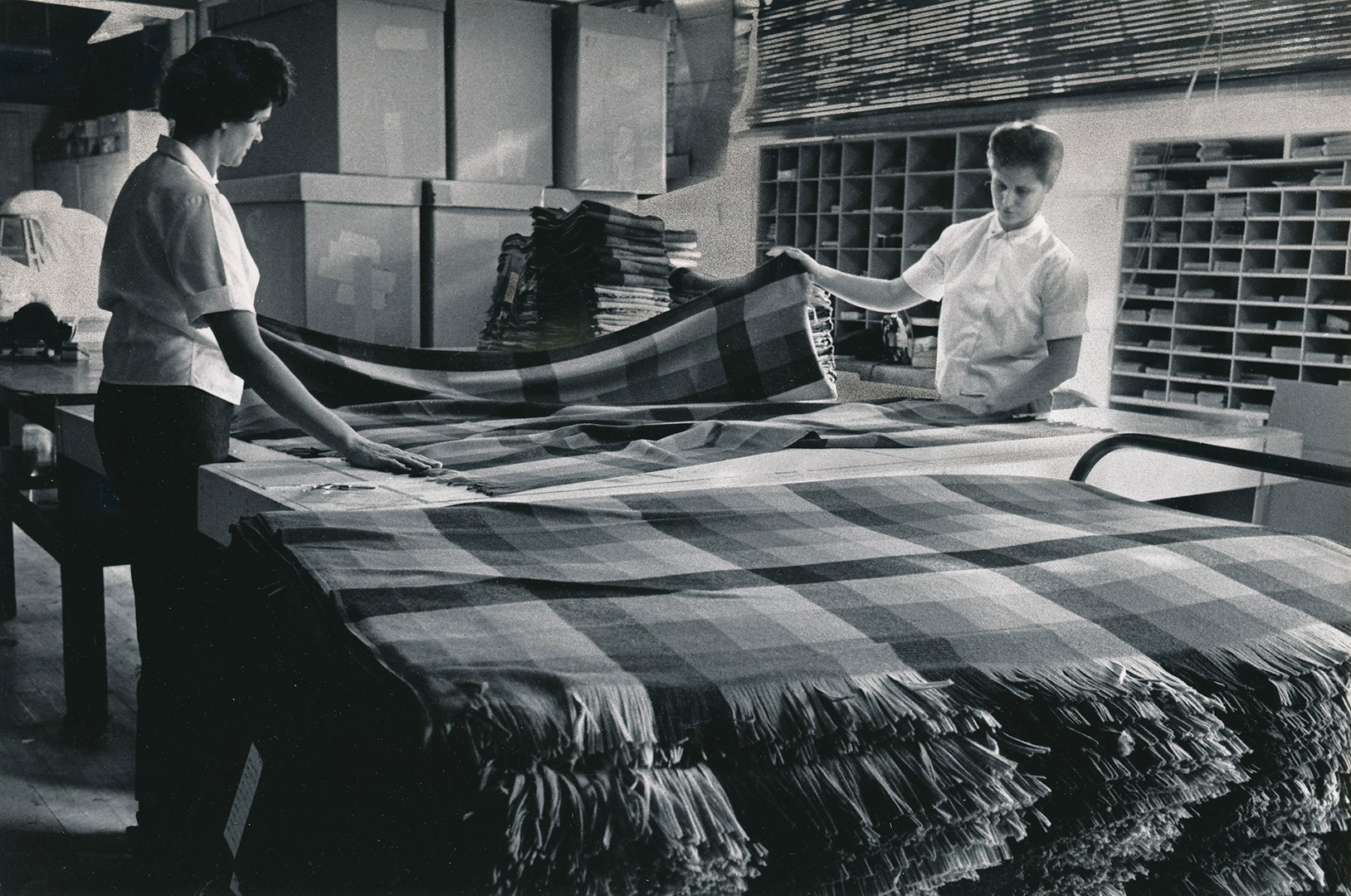 This photo from the mid-1900s shows the old cut and sew process at Faribault Woolen Mill. The final steps include sewing edges, hemming and stitching.
