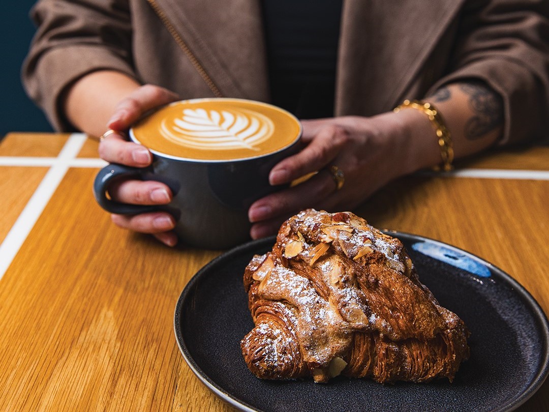 A customer enjoys a latte and an almond croissant. Pastries at The Lobby Coffee & Leisure are made by Patisserie 46.