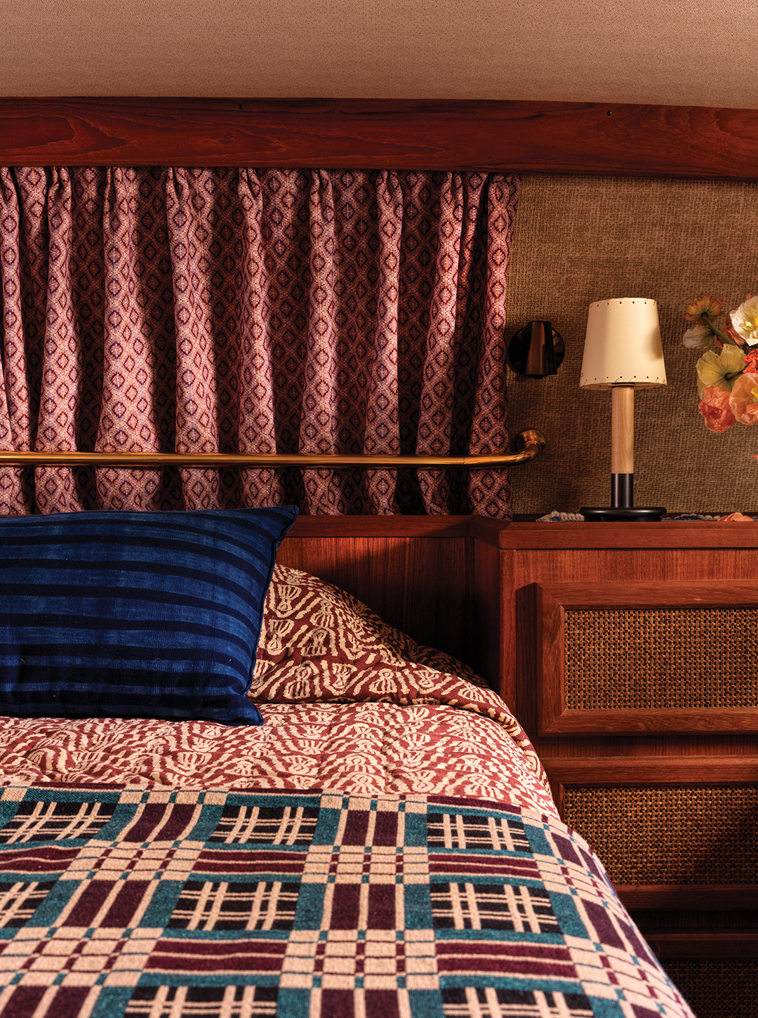The primary bedroom features a bold mix of patterns and colors. The bedspread is from Studio Ford, a Los Angeles-based textile studio that specializes in Indian block-printing. The blanket is from Gregory Parkinson, a designer who travels the world in search of handmade, multilayered woven blankets, pillows and throws. The curtains are made by weaver Christine Ann Novotny of Grand Marais, Minnesota.